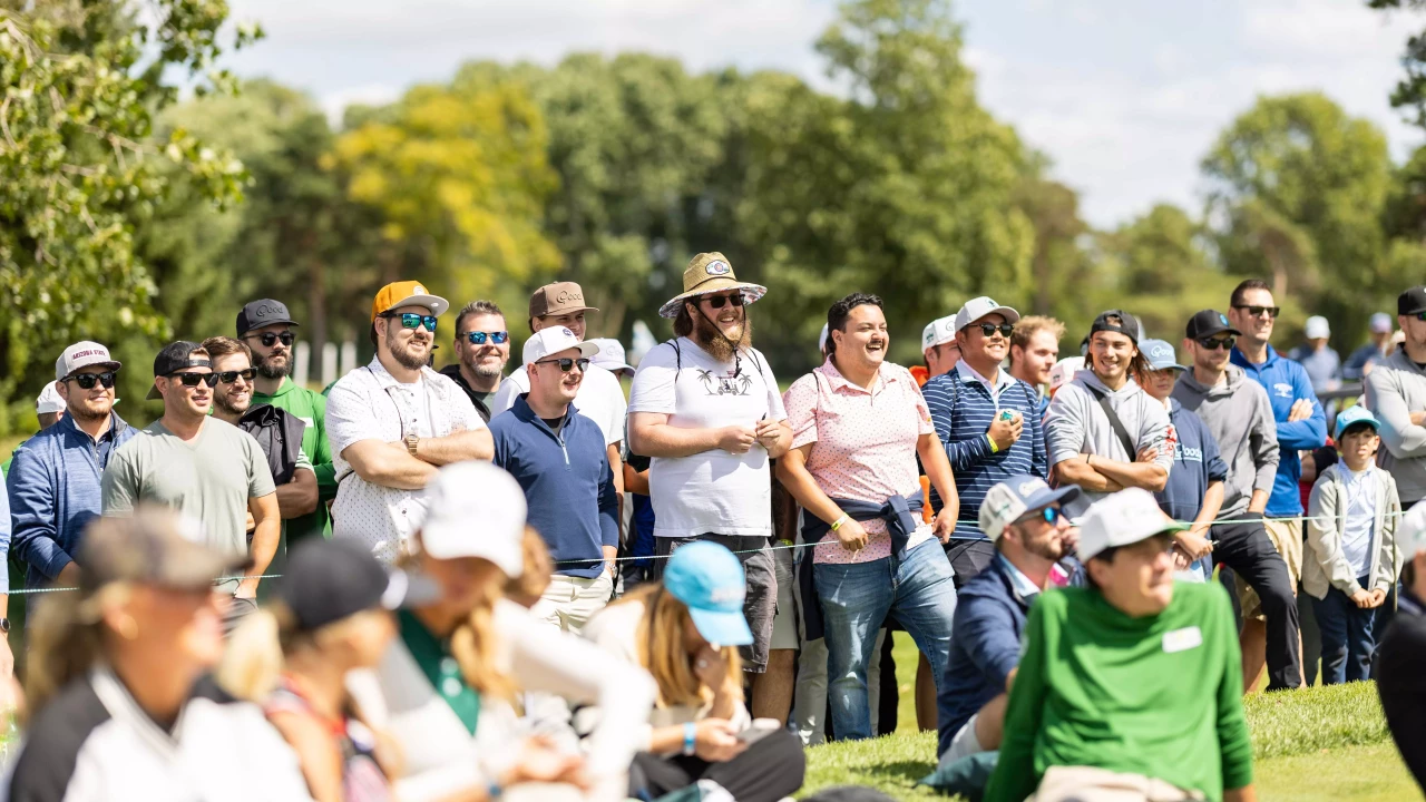 Spectators gathered along the fairway watching play.
