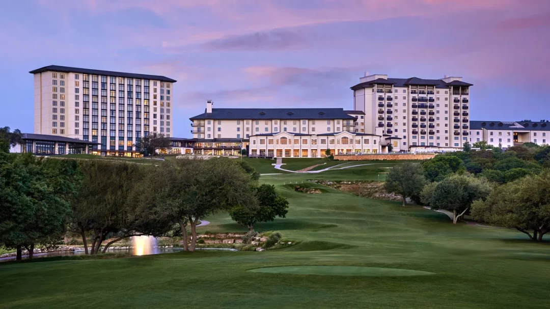 Wide view of Omni Barton Creek resort overlooking a golf course at dusk in Austin, Texas.